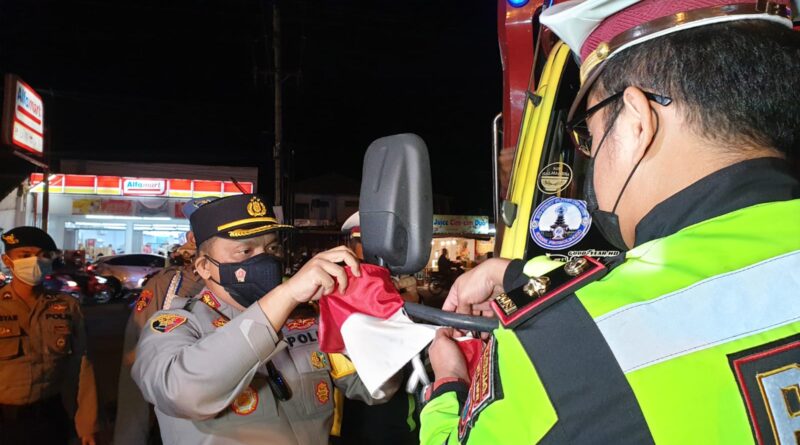 Polresta Banyuwangi Memasang Bendera Merah Putih Kecil ke Kaca Spion Truk yang Melewati Pelabuhan Ketapang, Sabtu, 31 Juli 2021 (Foto: IST)