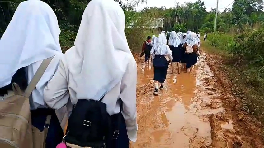 Kondisi jalan rusak dan berlumpur di Desa Muara Jernih, Kecamatan Tabir Ulu, Kabupaten Merangin, Jambi, kian memprihatinkan. Akibatnya, para siswa SMP Negeri 32 Merangin terpaksa berangkat ke sekolah tanpa alas kaki pada Minggu (3/5/2026). (Foto: IST/Dewi Yulianti)