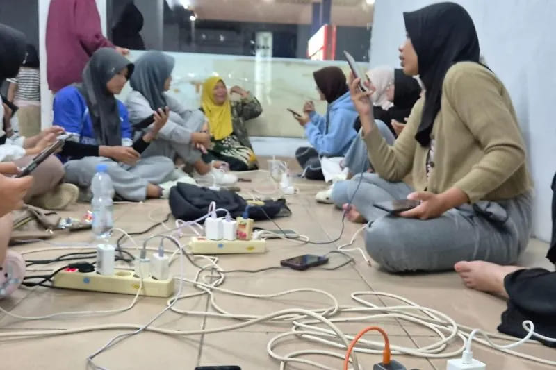 Sejumlah warga mengisi daya gawai di lokasi yang tidak terdampak pemadaman listrik di Kota Padang Jumat (22/5/2026) malam. (Foto: ANTARA/Dokumentasi Pribadi)