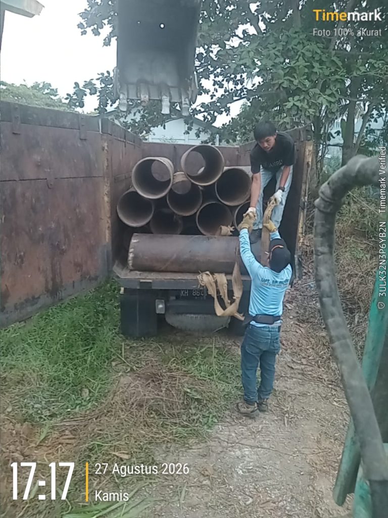 Dua orang warga Desa Muara Wakat saling bantu dalam mengangkat pipa gorong-gorong ke dalam truk. (Foto: IST/Carli Silitonga)