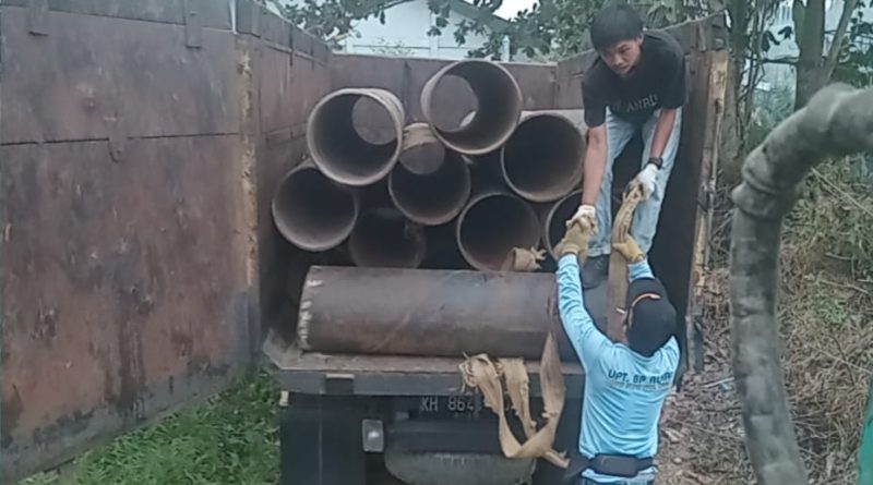 Dua orang warga Desa Muara Wakat saling bantu dalam mengangkat pipa gorong-gorong ke dalam truk. (Foto: IST/Carli Silitonga)